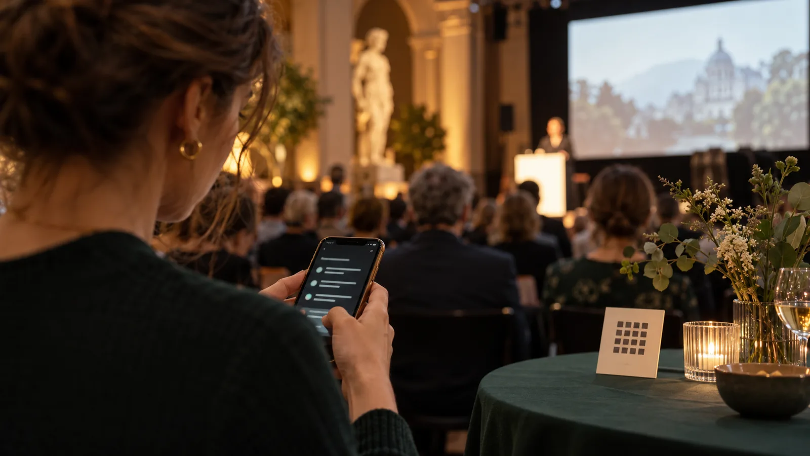 Ein Gast liest auf einem Smartphone neben dem Empfangstisch einer Veranstaltung.